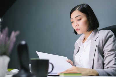 Young woman using phone while sitting on table