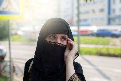 Portrait of a muslim woman in black national clothes on a city street, close-up.