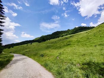 Scenic view of road amidst field against sky