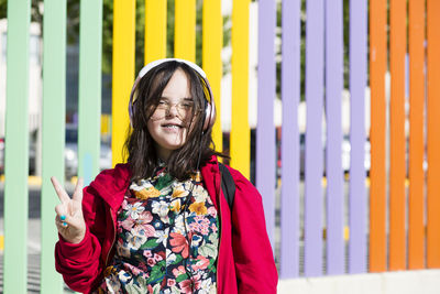 Teenager with down syndrome using smartphone, headphones, peace sign