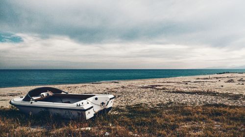 Abandoned boat on beach against sky