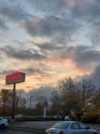 Road sign against sky during sunset