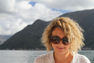 Portrait of smiling woman wearing sunglasses against mountain