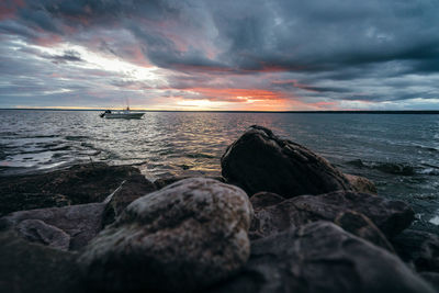 Rocks by sea against sky during sunset