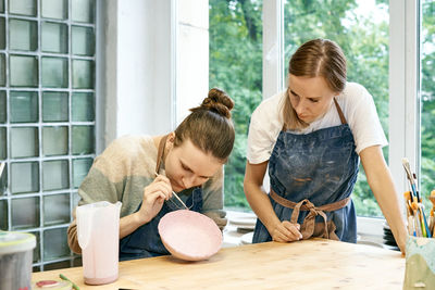 Friends working in pottery shop during day