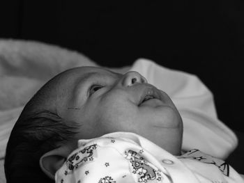 Close-up of cute baby lying against black background