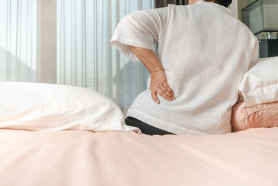 Rear view of man relaxing on bed