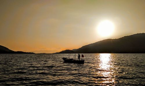 Silhouette boat in sea against sky during sunset