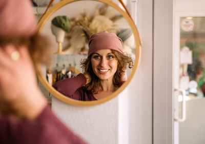 Happy woman smiling in reflection of studio mirror