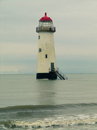 Lighthouse by sea against sky