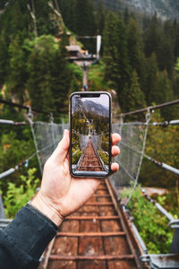 Man photographing with mobile phone - iphone framed picture of hanging bridge 