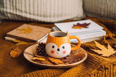 Autumn cozy home. fall cozy reading nook with a blanket, candles, autumn fall leaves, cup of coffee 