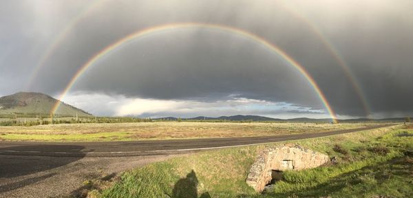 Scenic view of field against rainbow in sky