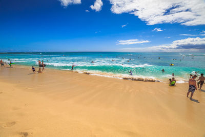 People at beach against sky