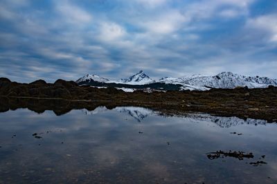 Scenic view of lake by snowcapped mountains against sky