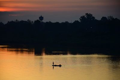 Silhouette boat in lake against sky during sunset