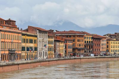 Buildings by river against sky in city