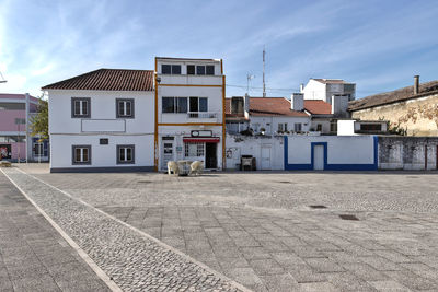 Empty road by buildings against sky