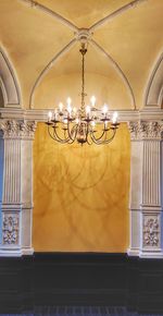 Illuminated chandelier hanging on ceiling of building