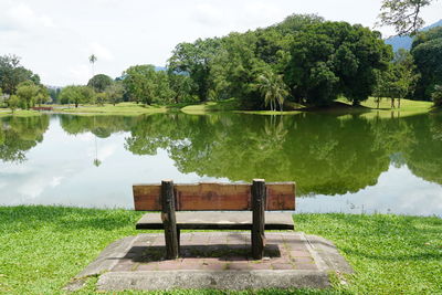 Rear view of woman sitting on bench by lake