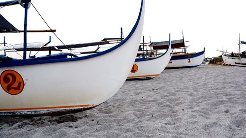 Boat moored on beach against sky