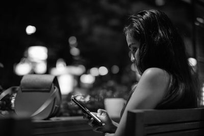 Midsection of woman using mobile phone while sitting outdoors