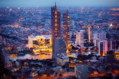 Aerial view of illuminated buildings in city at dusk