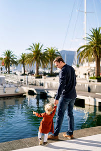 Father and son in water against sky