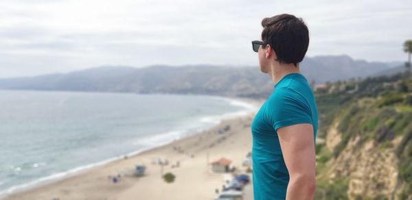 Side view of man looking at sea while standing on mountain