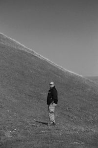 Rear view of man standing on field against sky