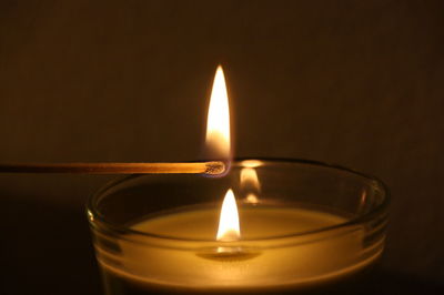 Matchstick lighting candle over plain background
