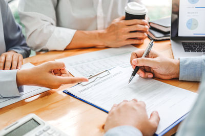 Midsection of business people working on table