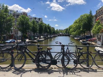 Bicycle parked by river against sky