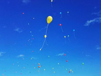 Low angle view of balloons flying against blue sky