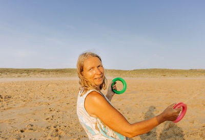 Woman playing in sand at beach against sky