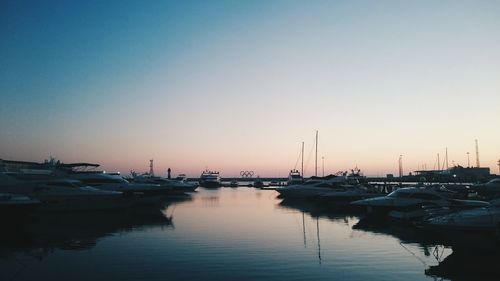 Sailboats moored on sea against sky during sunset