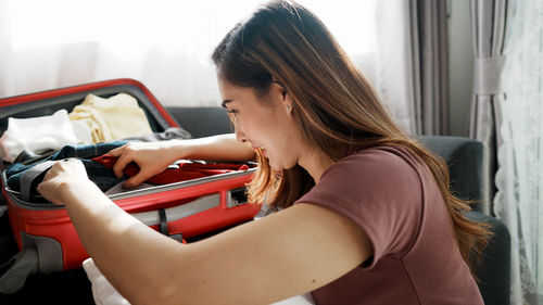 Close-up of woman packing suitcase at home