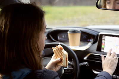 Rear view of woman holding ice cream in car