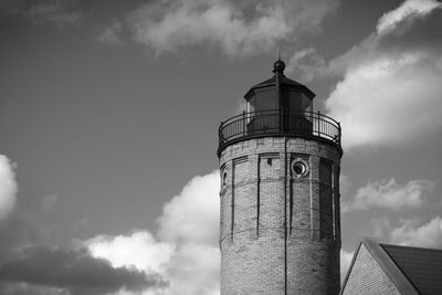 Low angle view of lighthouse by building against sky