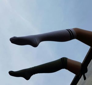 Low angle view of mannequin legs with socks hanging on roof against sky