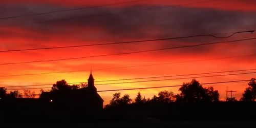 Silhouette trees and buildings against sky during sunset