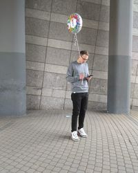 Man with balloon using mobile phone on footpath