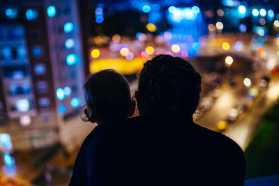 Rear view of woman standing in city at night