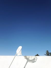 Low section of shoes against clear blue sky