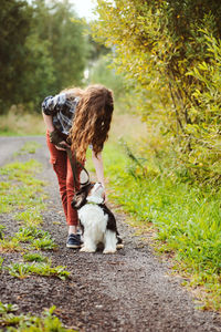 Full length of girl walking with dog on dirt road