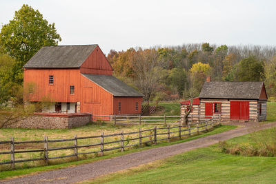 Historic colonial american farm scene, dirt road, log cabin and red barn.