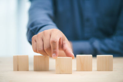 Midsection of businessman playing with toy blocks on table