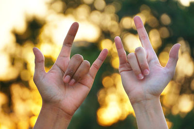 Close-up of hands gesturing against trees