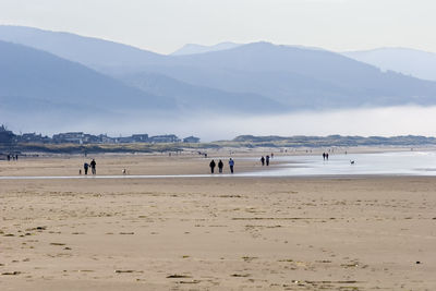 People at beach against mountains