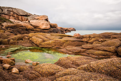 Close-up of rocks in sea against sky